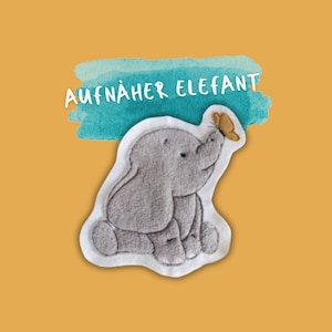 May include: A gray felt elephant applique with a white outline, sitting and looking up at a brown butterfly. The applique is labeled "AUFNÄHER ELEFANT" in white text on a blue watercolor background.