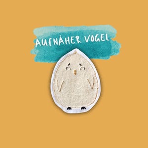 Könnte beinhalten: Weißer Filz-Aufnäher eines Vogels mit schwarzen Augen, einem gelben Schnabel und schwarzen Füßen. Der Vogel befindet sich auf einem hellblauen Aquarellhintergrund mit dem Text "AUFNÄHER VOGEL" in Weiß.