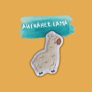 Könnte beinhalten: Ein weißer Filz-Lama-Aufnäher mit braunen Augen und einer rosa Nase. Der Aufnäher befindet sich auf einem hellblauen Aquarellhintergrund mit dem Text "AUFNÄHER LAMA" in weiß.