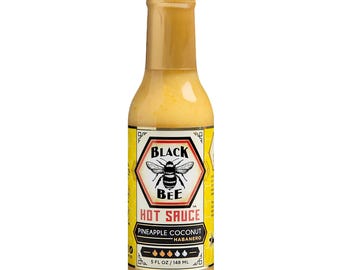 May include: A bottle of Black Bee Hot Sauce. The label features a bee illustration and the text "HOT SAUCE". The sauce is pineapple coconut habanero flavored. The bottle contains 5 fl oz / 148 mL of sauce.