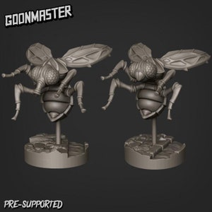 Puede incluir: Dos figuras de insectos grises estilizadas con ojos grandes, alas y patas articuladas. Cada insecto está montado sobre una base circular con una superficie texturizada. Los textos "GOONMASTER" y "PRE-SUPPORTED" son visibles.