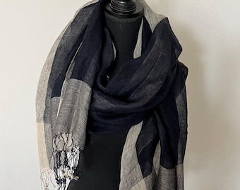 May include: A black and beige checkered scarf with fringe on the ends. The scarf is draped over a black mannequin.