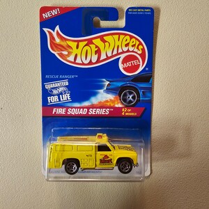 Peut inclure: Un camion de pompiers jouet en métal moulé sous pression de couleur jaune avec un logo "Fire Dept" rouge et blanc sur le côté. Le camion fait partie de la "Fire Squad Series" et est le numéro 2 sur 4 modèles. L'emballage est bleu et présente le logo Hot Wheels.