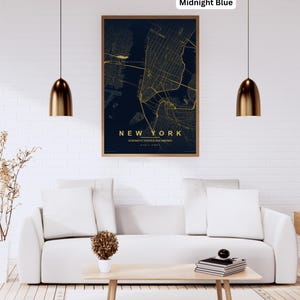 Könnte beinhalten: Eine gerahmte Karte von New York City in einem Mitternachtsblau-Farbschema mit goldfarbenen Straßen und Text. Der Text lautet "NEW YORK" und "VEREINIGTE STAATEN VON AMERIKA". Die Karte wird über einem weißen Sofa und einem Holztisch angezeigt.