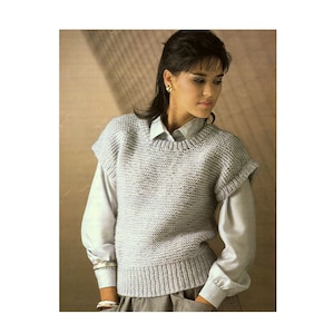 May include: A sleeveless knitted sweater in a light gray color. The sweater has a round neckline and a ribbed texture.
