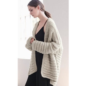 May include: A light beige knitted cardigan with a relaxed fit and long sleeves. The cardigan is made of a soft, textured yarn and has a simple, open front.
