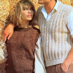 Puede incluir: Una mujer y un hombre visten chalecos de punto. El chaleco de la mujer es de color marrón liso, mientras que el del hombre es de color beige claro con canalé vertical. Ambos chalecos parecen estar hechos de un hilo texturizado, lo que sugiere una sensación cálida y acogedora.