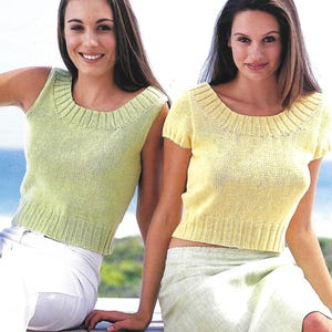 May include: Two women wearing sleeveless knit tops. The woman on the left is wearing a light green top and the woman on the right is wearing a yellow top.