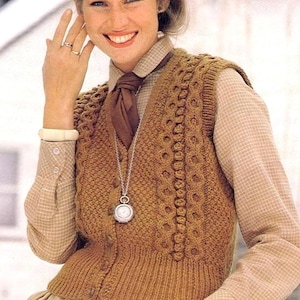 Puede incluir: Un chaleco de punto marrón con cierre de botón y un patrón de punto de cable. El chaleco se lleva sobre una camisa a cuadros con una corbata marrón. La persona lleva un collar de plata con un reloj de bolsillo.