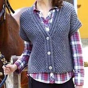 May include: A grey knitted waistcoat with a V-neck and short sleeves. The waistcoat has a button fastening and a textured pattern.