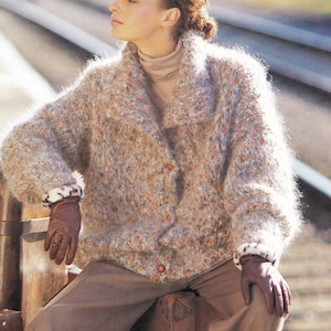May include: A textured, button-down cardigan in shades of beige, brown, and orange. The cardigan has a wide collar and is worn with brown gloves and a turtleneck. The cuffs feature a white and brown pattern.