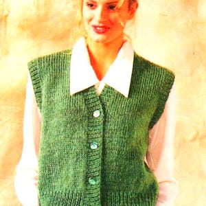 May include: A green knitted vest with a button-up front. The vest has a white collar and is worn over a white shirt.