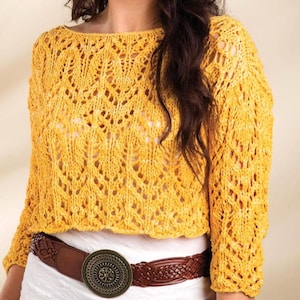 May include: A mustard yellow, open-weave knitted sweater with long sleeves and a boat neck. The sweater is worn with a brown, braided belt with a circular buckle. The knitwear's texture is visible, showcasing the intricate design.
