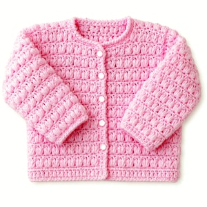 May include: A long-sleeved, light pink cardigan featuring a textured bobble stitch pattern throughout the body and sleeves. The garment has a round neckline and is fastened down the center front with five small, round, white buttons.