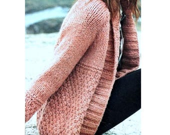 May include: A chunky knit cardigan in a soft rose color. The sweater features a textured stitch pattern on the lower portion and ribbed detailing on the sleeves and collar. This cozy, long-sleeved cardigan is perfect for layering.