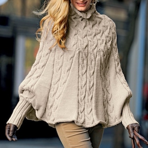 May include: A beige cable knit sweater with a turtleneck and long sleeves. The sweater has a loose fit and a slightly flared hem.