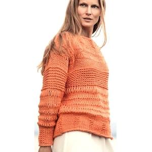 May include: An orange knitted sweater with a round neckline and long sleeves. The sweater has a textured design with horizontal ribbed sections and openwork details. The garment is made of a soft, possibly wool, material.