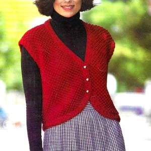 May include: A red, textured, button-down vest with a V-neck. The vest is worn over a black turtleneck and a black and white checkered skirt. The vest has three silver buttons.