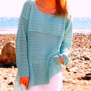 May include: A light blue crochet sweater with a loose fit and a wide, open neckline. The sweater has a delicate, open-stitch pattern throughout.