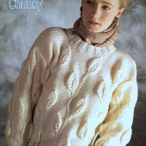 May include: A white knitted jumper with a leaf pattern. The jumper is chunky and has a crew neck. The model is wearing a brown scarf.