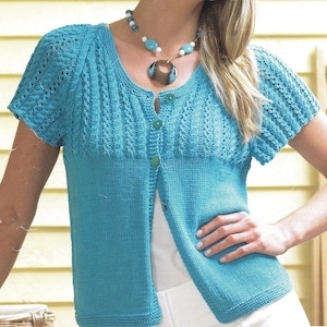 Könnte beinhalten: Türkisfarbene Strickjacke mit kurzen Ärmeln und Knopfleiste. Der obere Bereich hat ein dekoratives Lochmuster, während der untere Teil einfacher gestrickt ist. Die Strickjacke ist Teil einer Strickwarenkollektion.