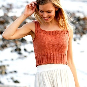 May include: A knitted tank top in a burnt orange colour with a square neckline. The tank top is cropped and has a ribbed texture.
