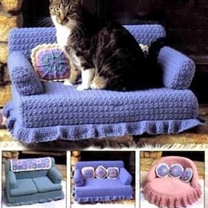 May include: A crocheted pet sofa in periwinkle blue with a ruffled base and a square accent pillow. The sofa features a textured stitch pattern and armrests. Additional variations include a blue sofa with a patterned throw and a pink round sofa.