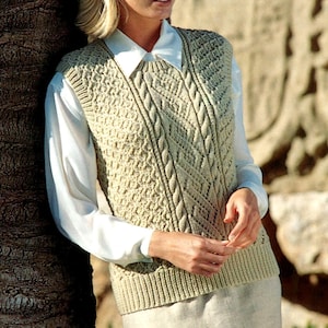 Puede incluir: Un chaleco de punto beige con un patrón texturizado y detalles de punto trenzado. La prenda sin mangas se lleva sobre una camisa blanca con cuello. El chaleco tiene un dobladillo acanalado y un cuello redondo. El estilo general es clásico y preppy.