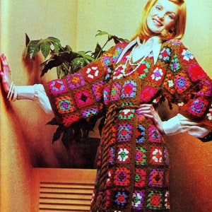 May include: A brown crochet dress with a colourful geometric pattern. The dress has a long, flowing skirt and a fitted bodice. The dress is belted at the waist with a brown cord.