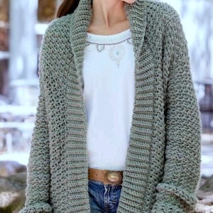 Puede incluir: Un c&aacute;rdigan largo de color gris con cuello chal y mangas largas. El c&aacute;rdigan est&aacute; hecho de un hilo suave y texturizado y tiene un corte holgado.