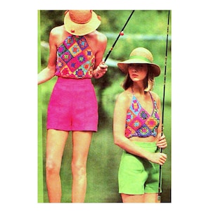 以下が含まれることがあります： カラフルなかぎ針編みのホルタートップとショートパンツを着た2人が、釣り竿を持っています。一人はピンクの服、もう一人はグリーンの服を着ています。どちらも麦わら帽子をかぶっています。かぎ針編みのトップスは、明るい色のパッチワークデザインです。