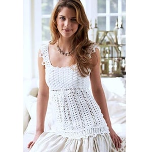 Könnte beinhalten: Ein weißes Häkeltop mit quadratischem Ausschnitt und einem figurbetonten Oberteil. Das Top hat ein zartes Spitzenmuster und einen Rüschen-Saum.