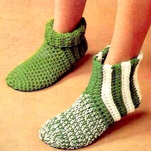 Peut inclure: Une paire de chaussons en crochet montant jusqu'aux chevilles. Un chausson est vert uni avec un revers replié. L'autre chausson présente un motif à rayures vertes et blanches sur la cheville et un point texturé vert et blanc sur le pied.