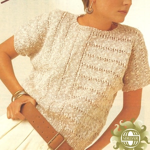 Op de afbeelding: Een beige gebreid topje met een delicaat opengewerkt patroon. Het topje heeft korte mouwen en een ronde hals. Het model draagt een bruine riem.