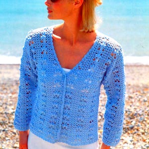 May include: A pale blue, open-weave crochet cardigan with a V-neck and long sleeves. The cardigan is buttoned up and worn over a white top. The image also includes the text "EASY CROCHET".