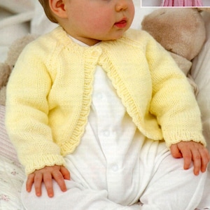 May include: A pale yellow knitted baby cardigan with a scalloped trim. The cardigan features long sleeves and is fastened with buttons. The baby is wearing a white onesie. The cardigan is made of soft yarn.