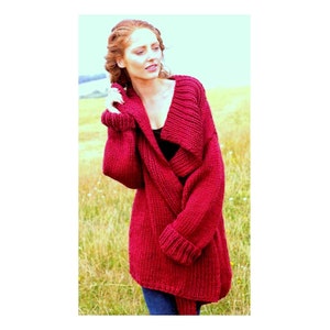 May include: A deep red knitted cardigan with a wide, folded collar and long sleeves. The cardigan is made of a chunky yarn and has a relaxed fit.