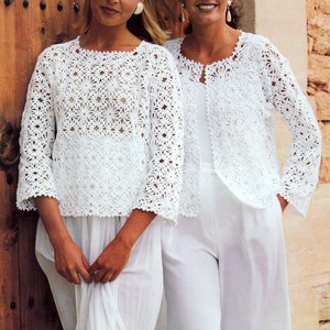 May include: Two white crocheted jackets with a floral pattern. The jackets are open in the front and have long sleeves. The jackets are worn by two women standing in front of a wooden door.