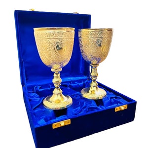 May include: Two gold-plated goblets with intricate designs, displayed in a blue velvet box with gold clasps.
