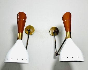 May include: A pair of white and brown wall-mounted lamps with adjustable arms. The lamps have a white shade with small holes and a brown, cone-shaped top.
