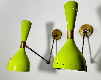 May include: Two lime green wall sconces with brass accents and black metal arms. The sconces have a unique design with a flared base and a pointed top.