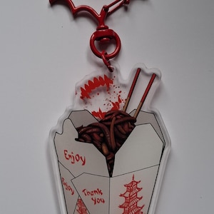 May include: A red Batman-shaped keychain with a clear acrylic charm. The charm features a Chinese takeout box design with noodles, chopsticks, and the words "Enjoy" and "Thank You".