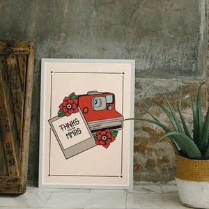 Könnte beinhalten: Gerahmter Kunstdruck mit einer Illustration einer roten Polaroid-Kamera, dem Text "THNKS FOR THE MMRS" und "FALL OUT BOY". Das Design enthält rote florale Elemente vor einem hellbeigen Hintergrund.