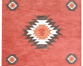 Puede incluir: Una alfombra roja con un diseño del suroeste. La alfombra tiene un gran patrón central de diamante con patrones de diamante más pequeños en las esquinas. La alfombra tiene un esquema de color marrón, blanco y naranja.