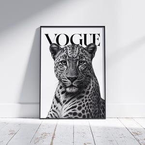 Könnte beinhalten: Schwarz-Weiß-Druck mit einem gerahmten Bild eines Leopardenkopfes. Über dem Leoparden steht das Wort „VOGUE“. Das Bild steht vor einer weißen Wand und einem Holzboden.