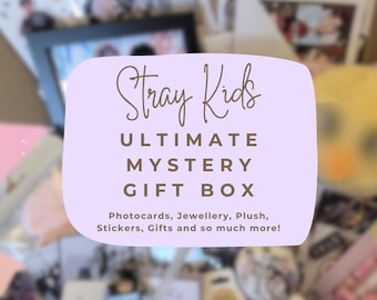 Può includere: Una confezione regalo con la scritta "Stray Kids ULTIMATE MYSTERY GIFT BOX" in un riquadro lilla chiaro. Il testo sottostante recita "Photocards, Jewellery, Plush, Stickers, Gifts and so much more!" Lo sfondo è pieno di vari oggetti.