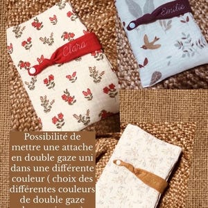 Puede incluir: Tres art&iacute;culos de tela doblados con bandas el&aacute;sticas personalizadas. Uno es crema con estampado floral rojo y "Clara" en una banda roja. Otro es azul claro con un dise&ntilde;o de p&aacute;jaros y hojas, con "Emilie" en una banda burdeos. El tercero es blanco con un estampado floral.