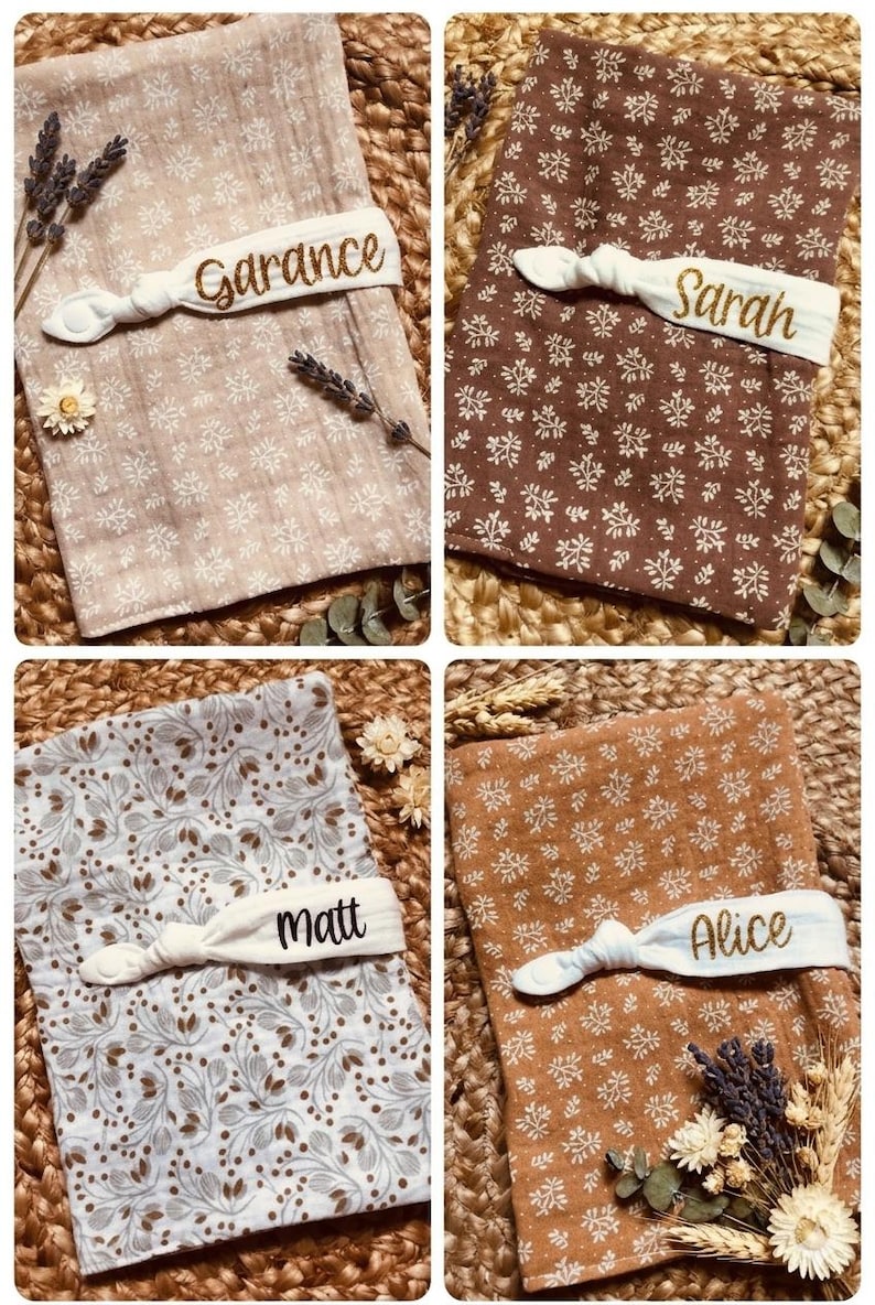 Puede incluir: Cuatro mantas de beb&eacute; personalizadas con estampados florales en varios colores: beige, marr&oacute;n, azul claro y naranja. Cada manta tiene una banda el&aacute;stica blanca con un nombre bordado en dorado: Garance, Sarah, Matt y Alice. Flores secas y espigas de trigo dispuestas alrededor.