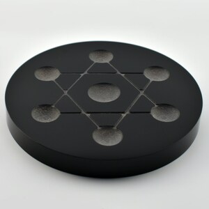 May include: Black obsidian crystal charging plate with a geometric design and seven indentations for crystals.
