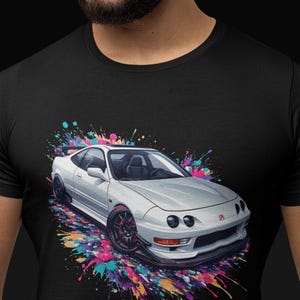 May include: A white Honda Civic with colorful paint splatters on a black t-shirt. The car has a black front bumper and black wheels.